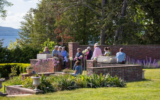 A group gathers along low brick walls surrounding the flower gardens at the Shelburne Farms Inn.