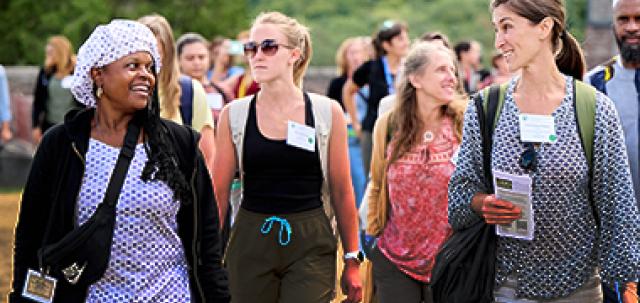 A large group of educators smile while talking on a walking tour of Shelburne Farms