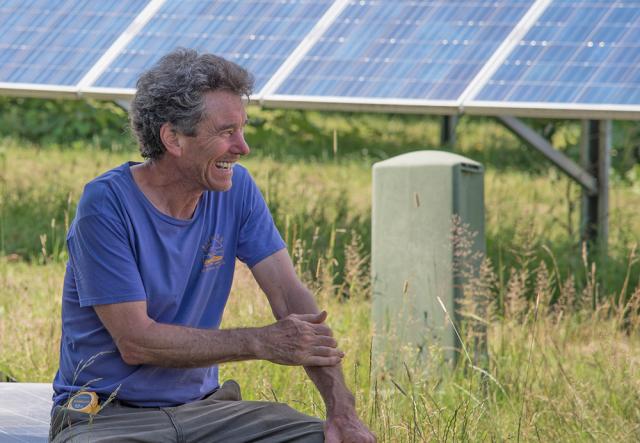 Marshall Webb in blue shirt sitting in front of a solar field