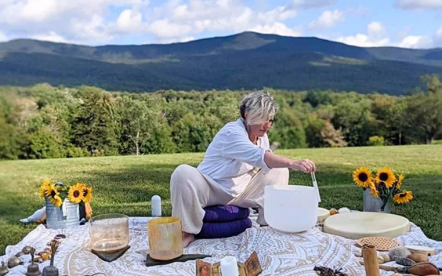 Melinda Kinzie with sound healing equipment outdoors.